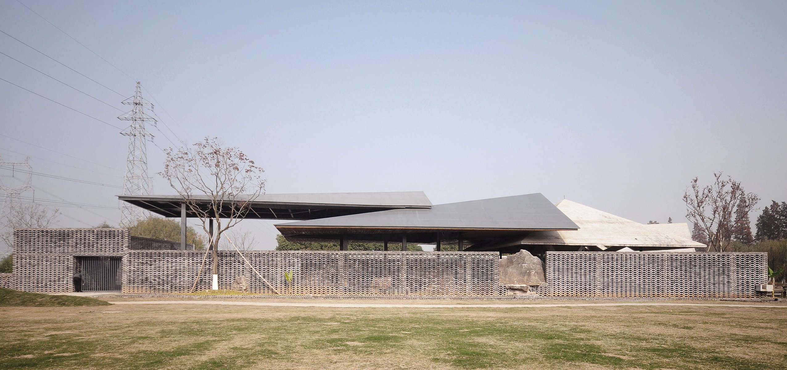 Building façade with dark grey modern exterior cover, ARCHITECTURE CHINA RE/DEFINE TRADITION in beige and white font above and below.