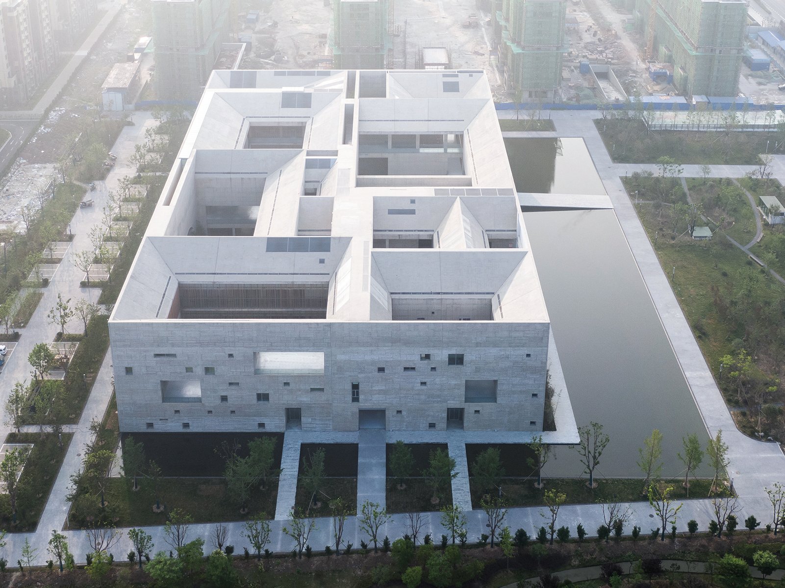 Building façade with dark grey modern exterior cover, ARCHITECTURE CHINA RE/DEFINE TRADITION in beige and white font above and below.