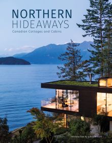 Stunning shot of modern glass building with flat moss roof poking out of Canadian forest near lake, Northern Hideaways in blue font above.