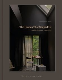 Book cover of The Homes That Shaped Us: People, Places, and Possibilities; featuring a dark interior with a chair and table below a skylight. Published by Images Publishing.