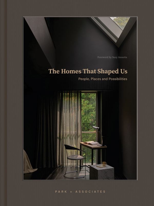 Book cover of The Homes That Shaped Us: People, Places, and Possibilities; featuring a dark interior with a chair and table below a skylight. Published by Images Publishing.