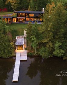 Book cover of Beautiful Houses by the Water: Living at the Water's Edge, featuring a pianist playing piano in living room interior with large windows, overlooking pond with fountain. Published by Images Publishing.