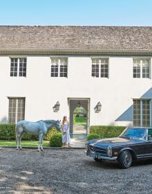 Two white horses grazing in front of single storey house, with topiary hedges, on cover of 'Equestrian Life in the Hamptons', by Images Publishing.