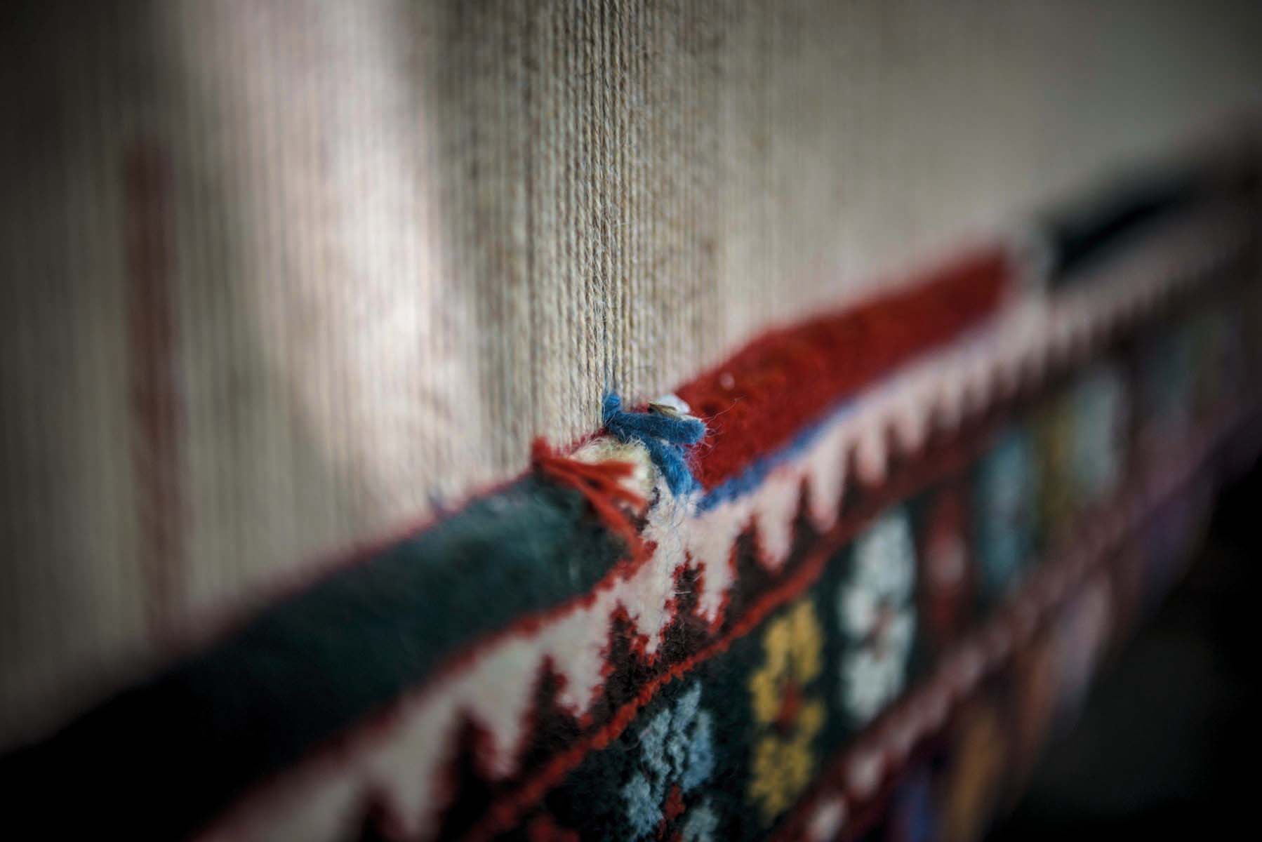 Montage of colourful pattered rugs, on white cover, The Handmade Carpet in bronze font on white centre square