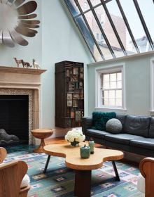 Interior designer Alexa Hampton's living room project, red wallpaper, patterned rug, fireplace, on cover of 'Art Underfoot, The Nazmiyal Collection', by Hali Publications.