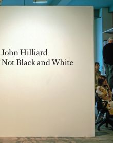 'John Hilliard: Not Black and White', in black font on white board, within office space, by Ridinghouse.