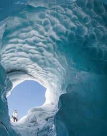 Book cover of Our Frozen Planet: A Photographic Journey Through the World of Snow and Ice, with a skier walking through a snow covered landscape. Published by Papadakis.