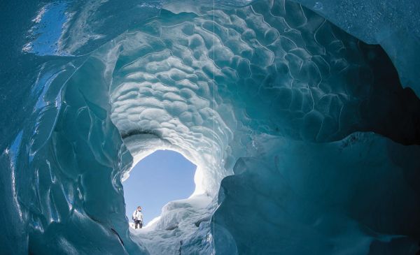 Book cover of Our Frozen Planet: A Photographic Journey Through the World of Snow and Ice, with a skier walking through a snow covered landscape. Published by Papadakis.