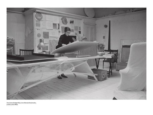 Bridget Riley sitting on a table, 'Bridget Riley: A Very Very Person', in white, and pink font to left side, by Ridinghouse.