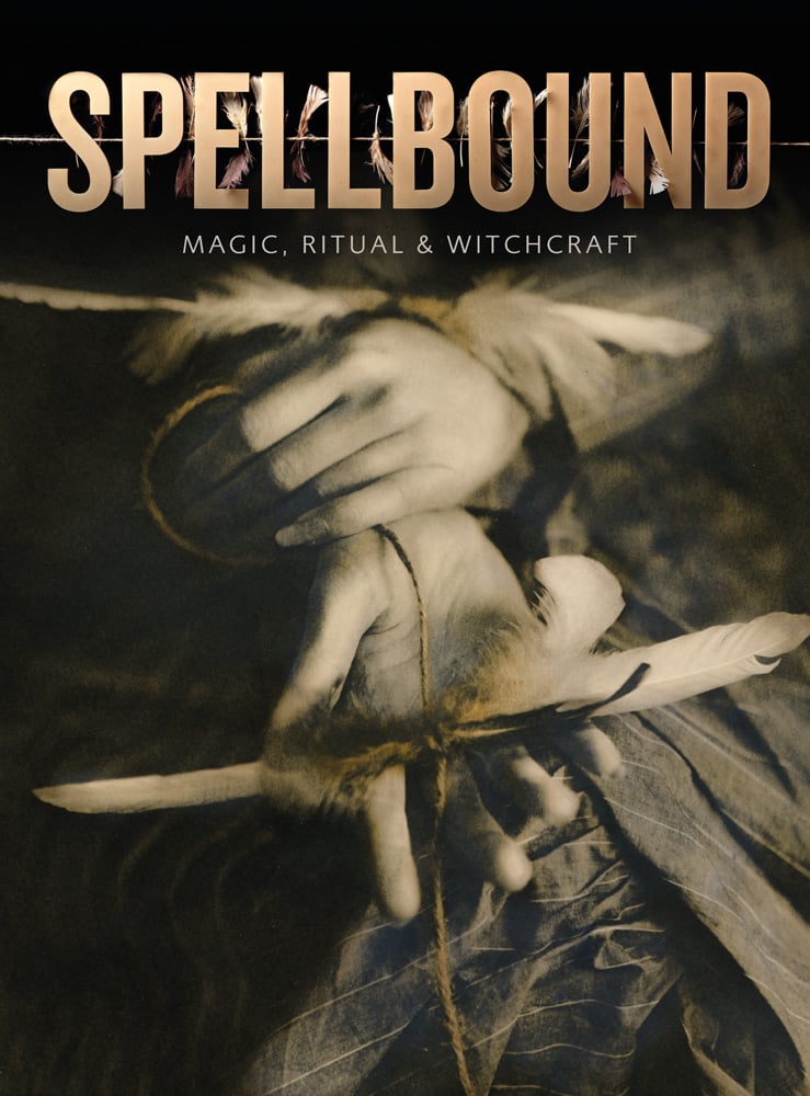 Pair of hands holding bird feathers threaded with string, on cover of 'Spellbound, Magic, Ritual and Witchcraft', by Ashmolean Museum.