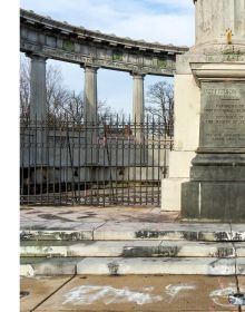 Grey statue covered in graffiti, with a placard, on black cover of 'Monument Avenue', by Circa Press.