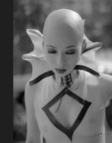 Female fetish model with bald head wearing white skin tight top with vampire collar, on cover of 'Steve Diet Goedde, Extempore', by Circa Press.