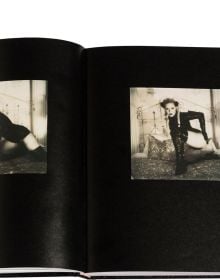 Blonde model in long black PVC gloves posing on bed, on black wood-effect cover of 'Boudoir', by Circa Press.