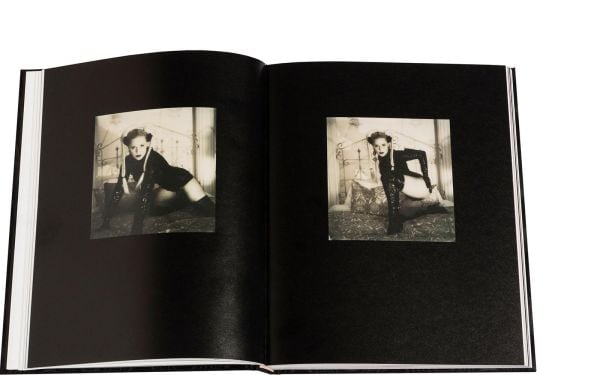 Blonde model in long black PVC gloves posing on bed, on black wood-effect cover of 'Boudoir', by Circa Press.