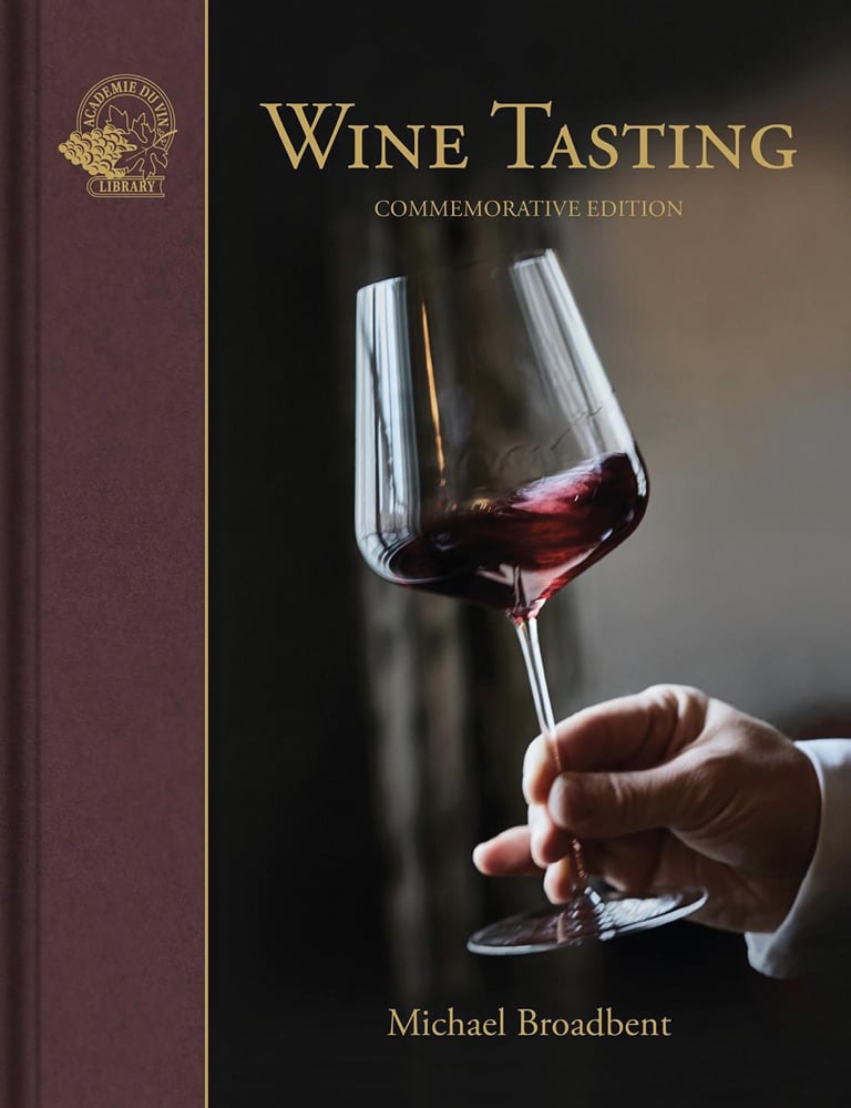 Hand gently swirls a glass of red wine, on cover of 'Wine Tasting', by Academie du Vin Library.
