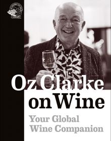 Smiling Oz Clarke in bird print shirt, holding glass of wine in hand, on cover of 'Oz Clarke on Wine, Your Global Wine Companion' by Academie du Vin Library.