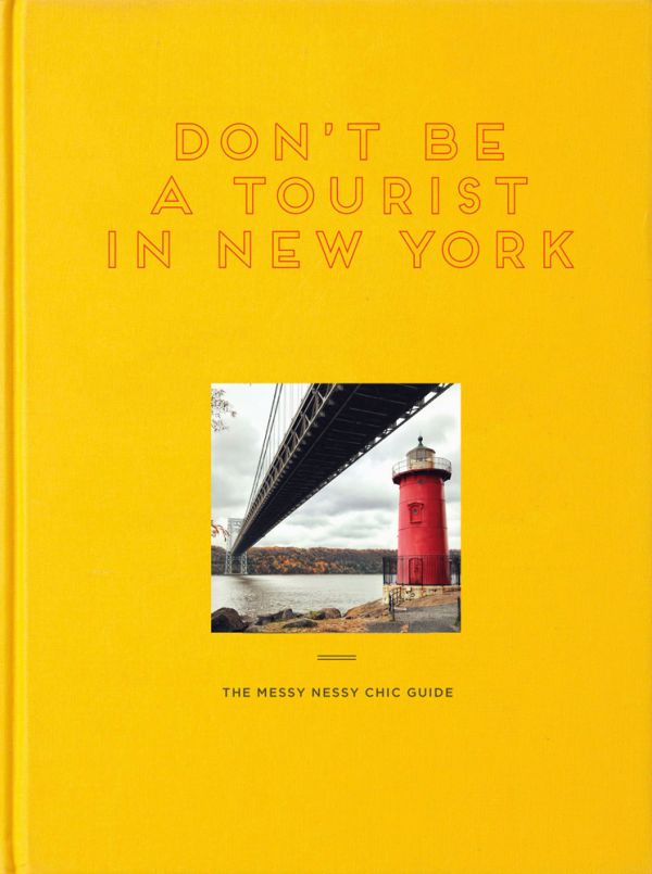 Yellow book cover of Don't Be a Tourist in New York, with a little red lighthouse under great gray bridge on Hudson River. Published by 13 Things Ltd.