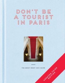 Aerial view of red stairs leading down to black and white checked tiled floor, DON'T BE A TOURIST IN PARIS, in red stencilled font above, on pale blue cover.