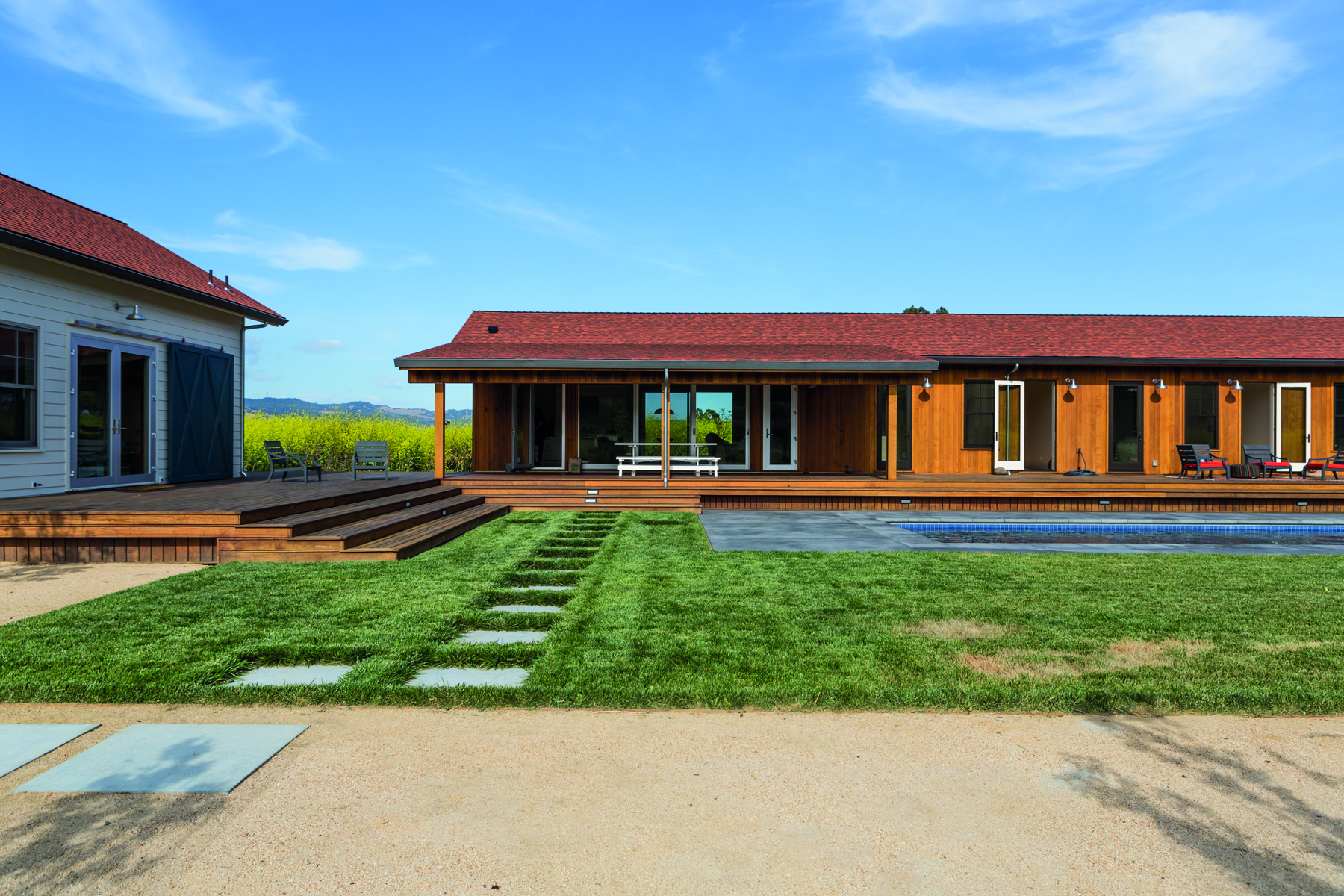 Single storey wood house with low steps leading to swimming pool, Pacific Modern in white font above