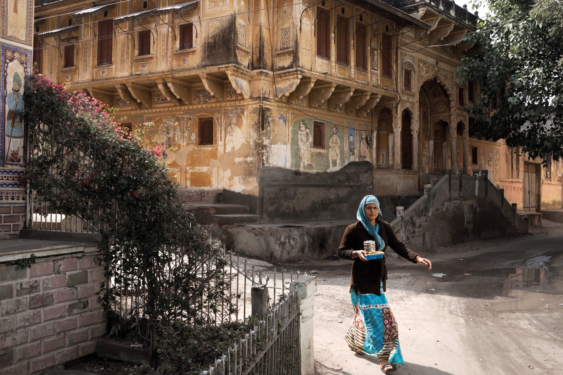 Fresco painting of Indian female, holding pot on head, brown handprint with Fantastic State of Ruin in black font above