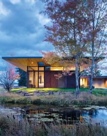 Contemporary flat roof building near lake and autumn trees, Inspired by Place Architects CLB in brown font above by Oro Editions.
