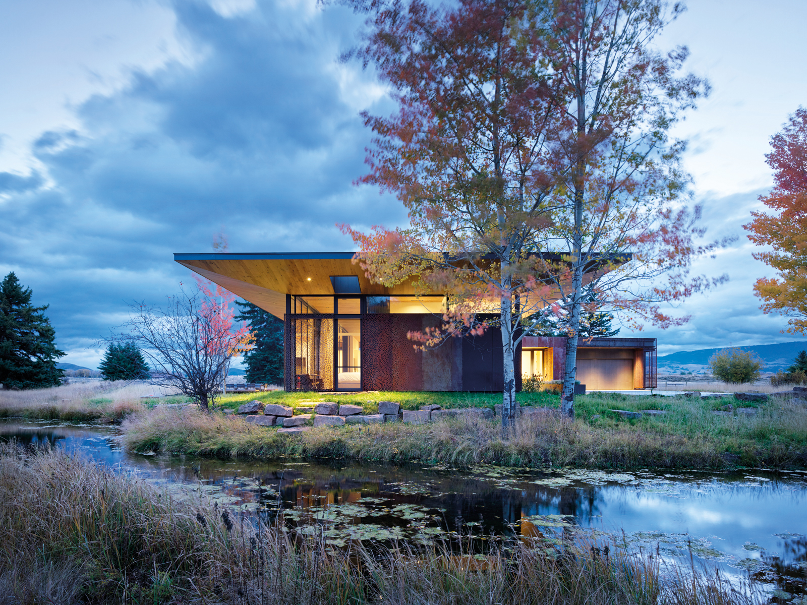 Contemporary flat roof building near lake and autumn trees, Inspired by Place Architects CLB in brown font above by Oro Editions.