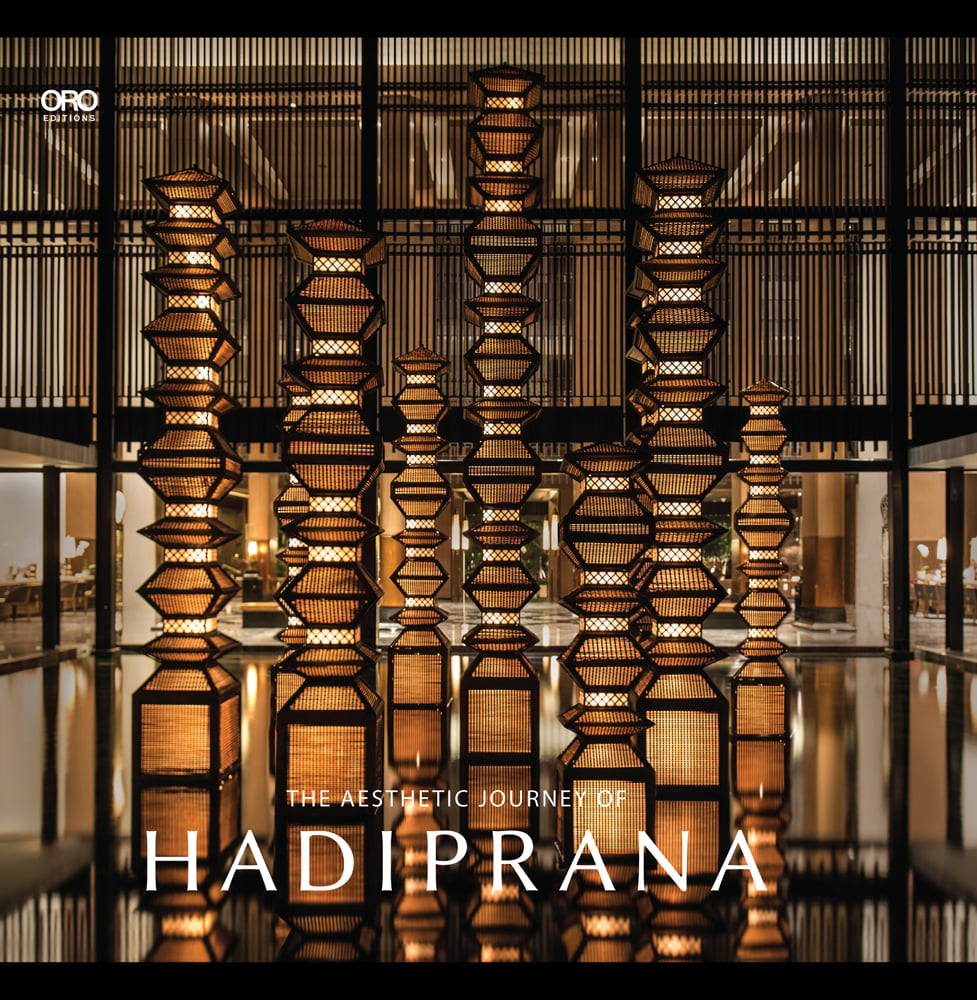 Tall wicker interior lights on a shiny floor, slated blinds behind, The Aesthetic Journey of Hadiprana in white font below