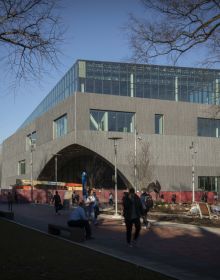 Modern curved wood and glass architectural structure, Library at Stoa Snohetta Public Space and Academic Mission in the Charles Library in white font.