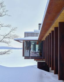 2 modern wooden buildings by Lake Muskoka, large trees and moss covered ground, The Architecture of Point William Shim Sutcliffe in white font to lower left.