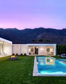 Building exterior with swimming pool below, on right side, girl peering through port hole in brick wall to left side, LIVE LEARN EAT in white font above.