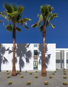 Building exterior with swimming pool below, on right side, girl peering through port hole in brick wall to left side, LIVE LEARN EAT in white font above.
