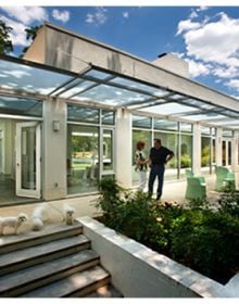 Modern glass residential building, under night sky, landscaped garden, TRIANGLE MODERN ARCHITECTURE in white font to top left.