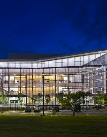 Modern glass residential building, under night sky, landscaped garden, TRIANGLE MODERN ARCHITECTURE in white font to top left.