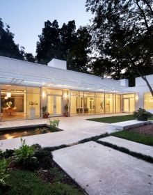 Modern glass residential building, under night sky, landscaped garden, TRIANGLE MODERN ARCHITECTURE in white font to top left.