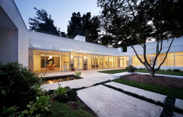 Modern glass residential building, under night sky, landscaped garden, TRIANGLE MODERN ARCHITECTURE in white font to top left.
