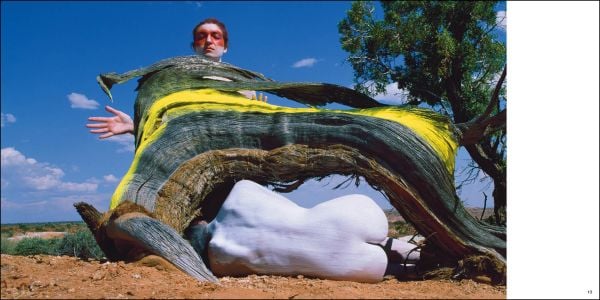 2 nude figure in red body paint and blue hair, 1 standing holding mannequin's legs, 1 sitting on edge of circular pool, blue cover, BODY MIRROR in white font above.