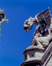 Stone dragon gargoyle on side of building, blue sky behind, ARCHES TO ZIGZAGS An Architectural ABC in white font above and below.