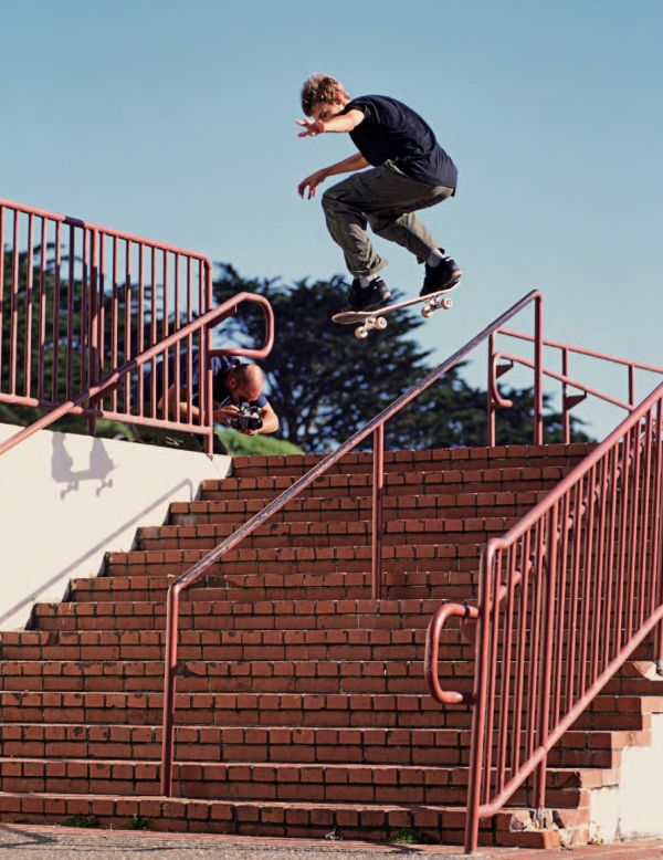 Book cover of Pete Thompson's 93 til, A Photographic Journey Through Skateboarding in the 1990s, with professional skateboarder Stevie Williams sitting on low brick wall smoking cigarette, with his board upside down on lap. Published by ORO Editions.
