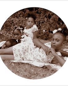 Blue cover with seated black model in white dress, holding scroll with Behind the Camera in white font above
