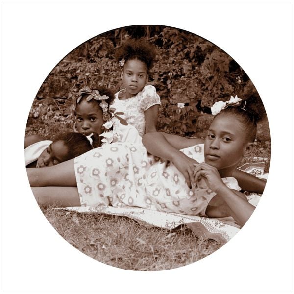 Blue cover with seated black model in white dress, holding scroll with Behind the Camera in white font above