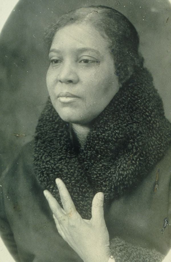 Blue cover with seated black model in white dress, holding scroll with Behind the Camera in white font above