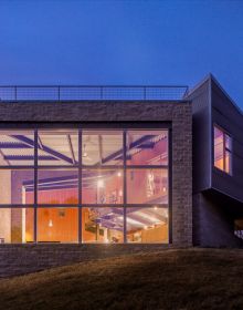 Single flat roof building illuminated by exterior lights under dusk blue sky with Framing The Valley in white font above