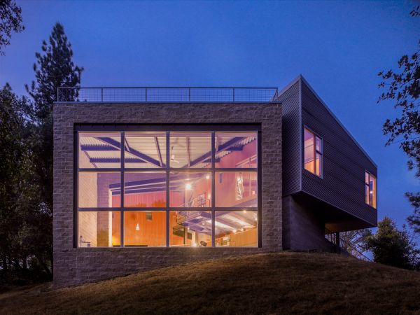 Single flat roof building illuminated by exterior lights under dusk blue sky with Framing The Valley in white font above