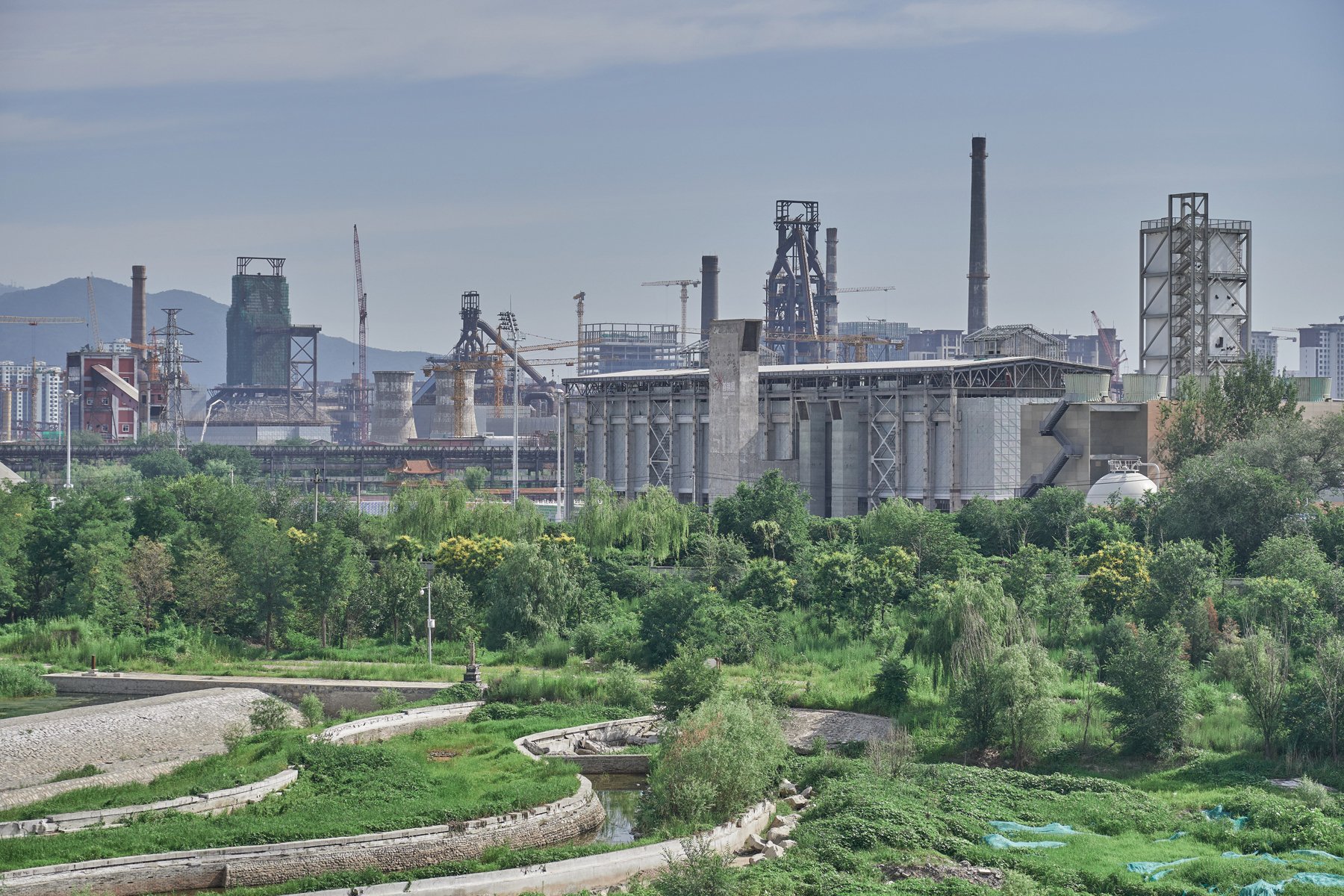 Exterior structure of derelict Shougang Oxygen Factory, THE STORY OF A SECTION in black font on white banner to left.