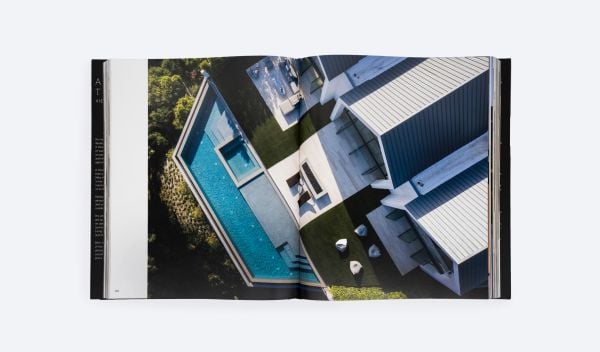 Modern, flat-roofed building with infinity pool and lounge chairs overlooking a green landscape. Published by ORO Editions.