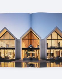 Modern, flat-roofed building with infinity pool and lounge chairs overlooking a green landscape. Published by ORO Editions.