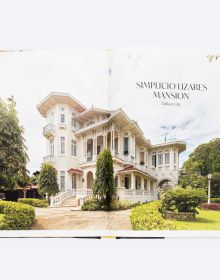 Grand interior with dark wood staircase, chandelier and stained glass interior windows, on cover of 'Houses that Sugar Built, An Intimate Portrait of Philippine Ancestral Homes', by ORO Editions.
