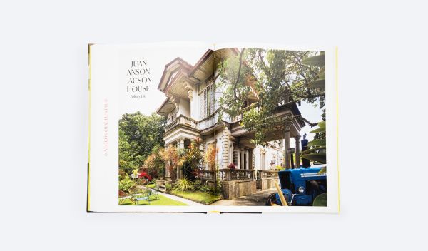 Grand interior with dark wood staircase, chandelier and stained glass interior windows, on cover of 'Houses that Sugar Built, An Intimate Portrait of Philippine Ancestral Homes', by ORO Editions.