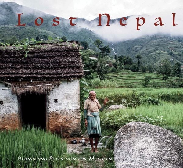 Book cover of Lost Nepal: A Photographic Memoir; featuring a figure standing in front of a hut with thatched roof, and misty mountains behind. Published by ORO Editions.