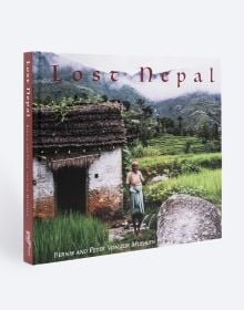 Book cover of Lost Nepal: A Photographic Memoir; featuring a figure standing in front of a hut with thatched roof, and misty mountains behind. Published by ORO Editions.